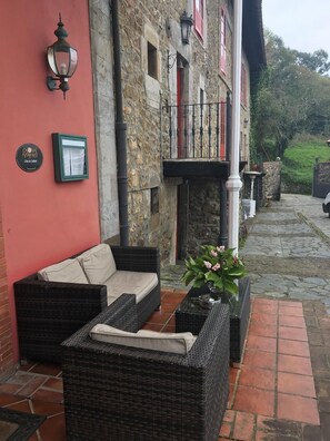 An outdoor seating area with wicker furniture and a potted plant. - Hotel Palacio De Libardon (Colunga)