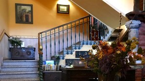 A checkered floor, a wooden table with a vase, a staircase with blue balusters, and a wall-mounted picture. - Hotel Palacio De Libardon (Colunga)