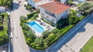 An aerial view of a two-story building with a swimming pool surrounded by greenery. - Mediterranean apartment with pool, barbecue, loungers - only 400 meters to the beach (Baska)