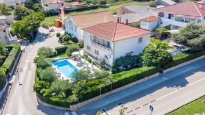 An aerial view of a residential area with a swimming pool, a road, and houses with red-tiled roofs. - Mediterranean apartment with pool, barbecue, loungers - only 400 meters to the beach (Baska)