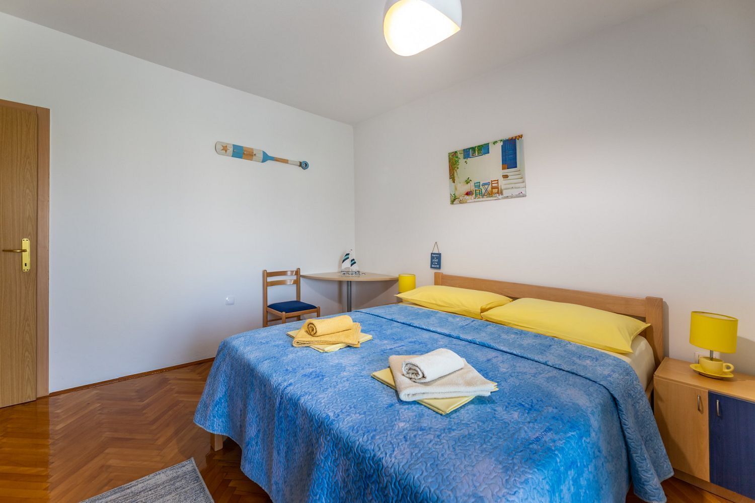 A bedroom with a bed, a desk, a chair, and a small table.
