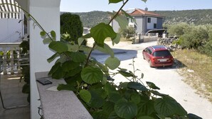 Un coche rojo estacionado en un camino de grava en una zona residencial, con una casa al fondo.