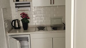 Una cocina compacta con horno empotrado, cafetera y una planta en maceta.