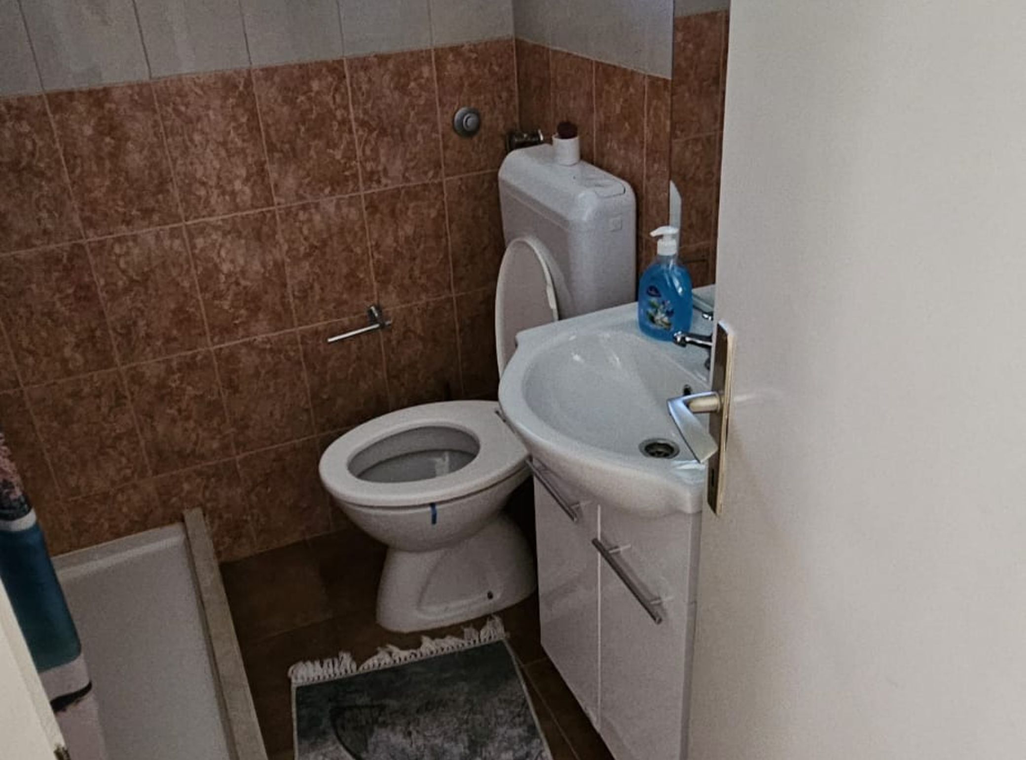 Et lille badeværelse med toilet, vask og håndklædeholder.