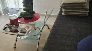 Una mesa de centro con superficie de vidrio, una bandeja, una pequeña planta en maceta y un cuenco rojo.