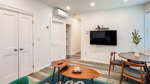 Un salon moderne avec un canapé vert, une petite table en bois et un coin repas avec des chaises.