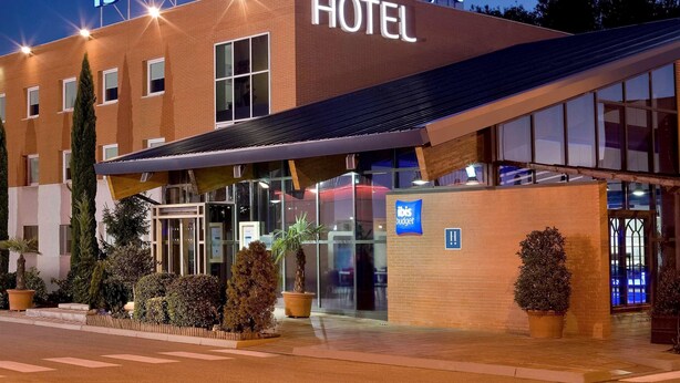 A hotel with a modern design, featuring a prominent sign that reads "ibis budget HOTEL." - Ibis Budget Madrid Alcala de Henares (Alcala de Henares)