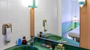 Un baño con un lavabo verde, un espejo y distintos artículos de aseo.
