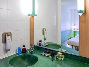 A bathroom with a green sink, a mirror, and various toiletries. - Ibis Budget Madrid Alcala de Henares (Alcala de Henares)