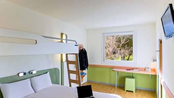 Una habitación de hotel moderna con una litera, un escritorio y una computadora portátil sobre la cama.