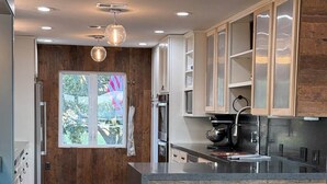 A modern kitchen with wooden accents, a large window, and a bar area. - Ultimate Lake Resort Xtravaganza | Lake Conroe | April Sound (Montgomery)