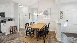 A modern kitchen with white cabinets, a wooden dining table, and black chairs.