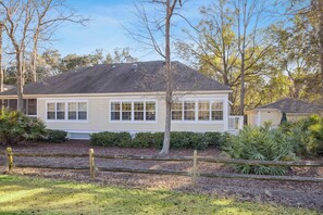 Une maison de plain-pied avec un porche à l’avant, un garage et une pelouse bien entretenue.