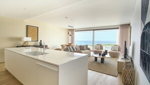 A modern living room with a large island, a sofa set, and a view of the sea.