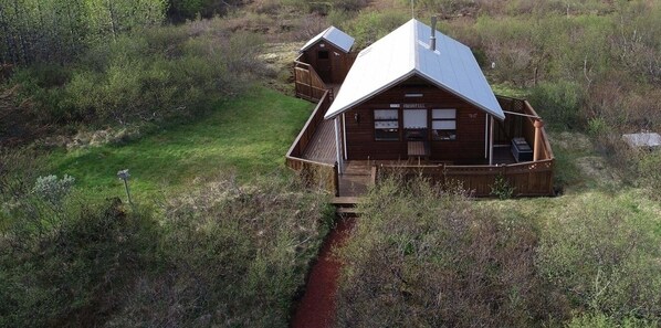 Eine Holzhütte mit Veranda, einer Terrasse und einem roten Weg, der zum Eingang führt.