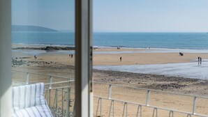 A beach view from a balcony with a railing and a chair. - 9 Strandways - Sea Views Parking Beach Access (Saundersfoot)
