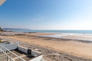 A beach view with a rocky shoreline, a sandy beach, and a clear sky. - 9 Strandways - Sea Views Parking Beach Access (Saundersfoot)