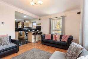 A modern apartment with a living room, kitchen, and dining area. - Little Haven - Cosy Tenby Apartment (Tenby)