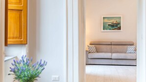 Ein Wohnzimmer mit einem beigen Sofa, einem Bild eines Segelboots und einer Zimmerpflanze.