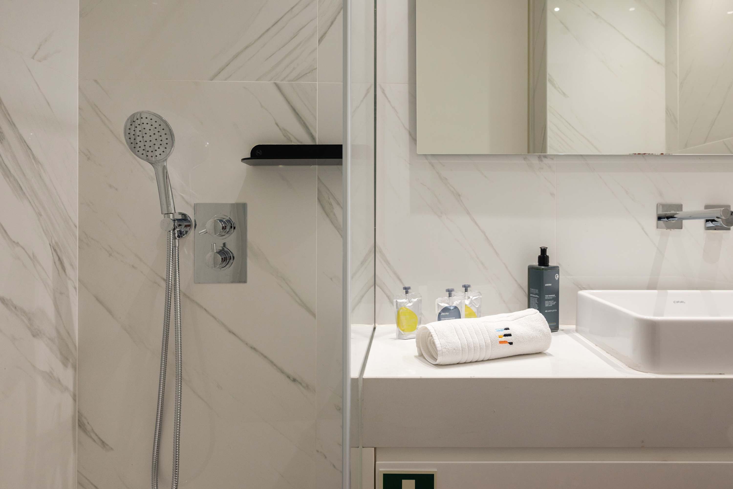 A modern bathroom with a shower, a sink, and a mirror.
