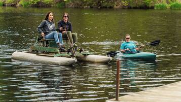 Two people on a small boat and one person kayaking nearby.
