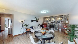 A modern living room with a fireplace, a round dining table, and a stone accent wall. - Snap, Set, Stay- Game Day Comfort Near It All (Canton)