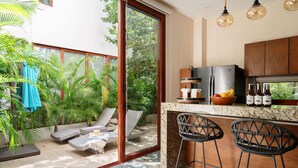 A modern kitchen with a refrigerator, bar stools, and a countertop with bottles. - WAYAK Luxury! 5BR Private Pool & Gym, 24/7Security (Tulum)