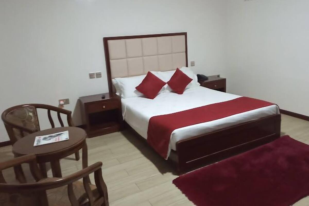 Una camera d'albergo con un letto, un comodino, una sedia e un tavolino.