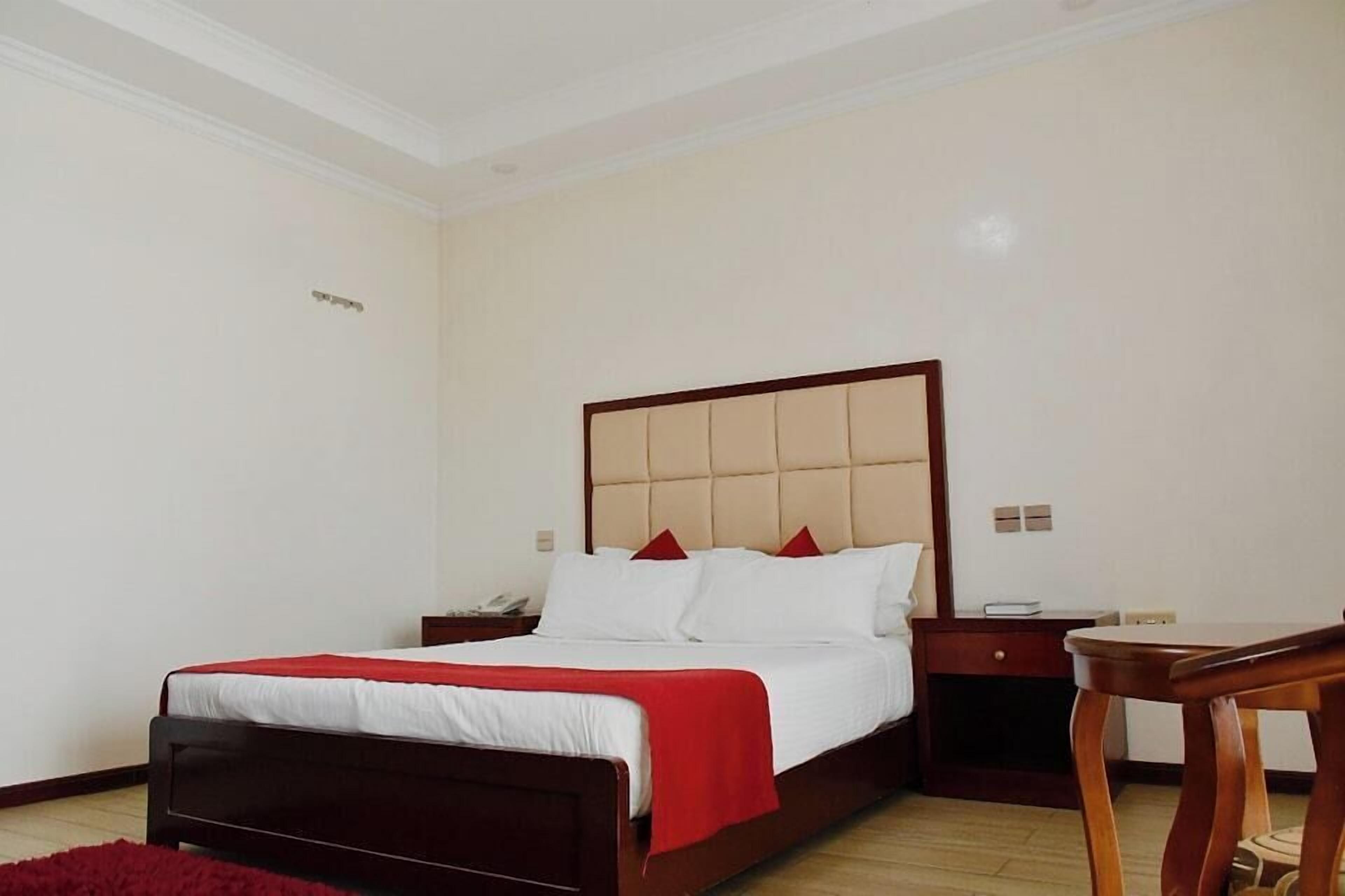 Une chambre d’hôtel avec un lit, des tables de chevet et un bureau.
