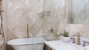 Un baño con bañera independiente, tocador con espejo y cabina de ducha con puertas de vidrio.