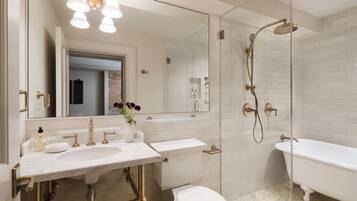 A bathroom with a white sink, a toilet, a bathtub, and a glass-enclosed shower area.