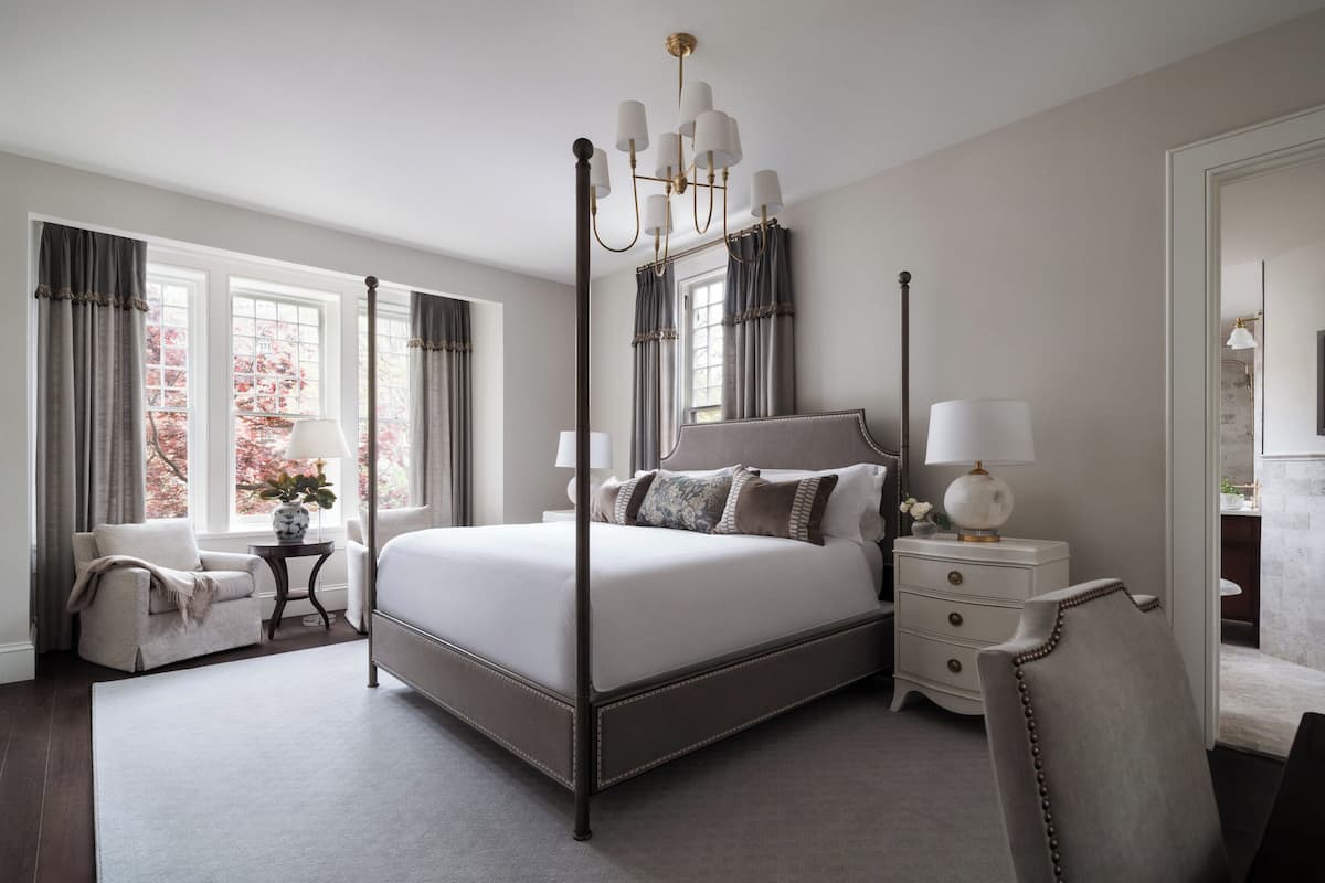 Une chambre à coucher avec un lit à baldaquin, une table de chevet avec une lampe, une chaise et une commode.