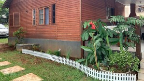 Uma casa de madeira com cerca branca de piquete, um pequeno jardim e um carro estacionado na entrada.