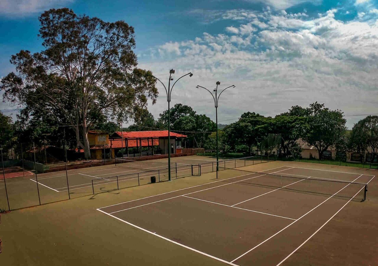 Una cancha de tenis al aire libre con un edificio de techo rojo al fondo.