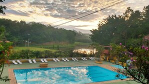 Piscina retangular com superfície de água azul translúcida, cercada por um deck verde.