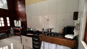 Cozinha com fogão, pia e armários. Há uma TV no canto e uma árvore de Natal ao fundo.