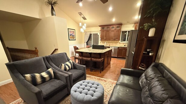 A living room with a gray sofa, a black leather sofa, and a gray ottoman. There is a dining area with a table and chairs in the background. - Heber Valley Base Camp: convenient location, modern amenities, pleasant spaces (Heber City)