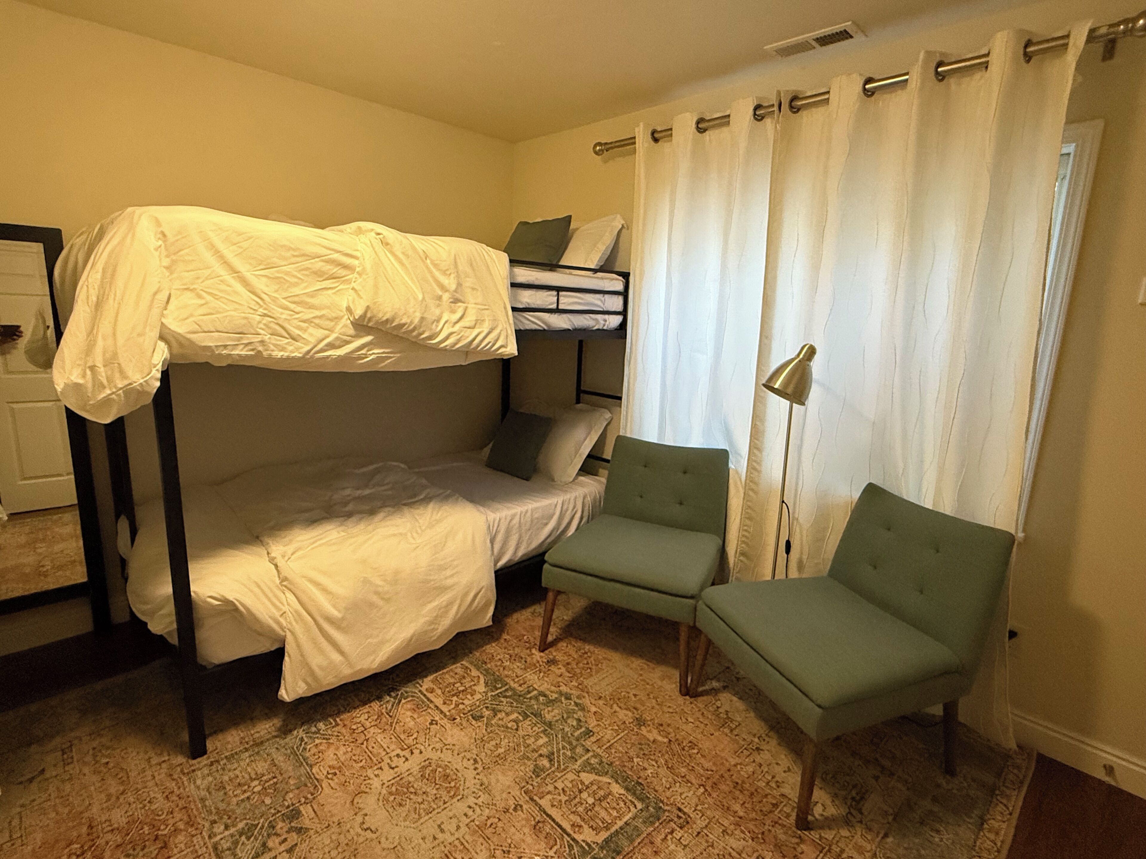 Ein Stockbett mit Schreibtisch und Stuhl, ein gemustertes Teppich und eine Lampe.
