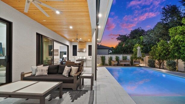 A modern outdoor living area with a pool, a sofa, and a dining table. - LUXE: Custom Beach Home w/Pool&Spa, Fire Pit, BBQ (Naples)