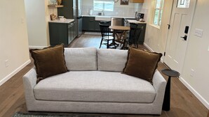 A modern living room with a grey sofa, brown cushions, a small side table, and a rug. - Serene Retreat Near Downtown (Prescott)
