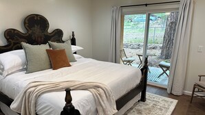 A bedroom with a large bed, a wooden headboard, and a view of the outdoors through a sliding glass door. - Serene Retreat Near Downtown (Prescott)