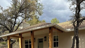 A house with a covered porch, a front door, and a small garden area with mulch and plants. - Serene Retreat Near Downtown (Prescott)