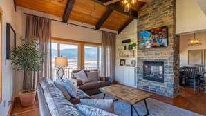 Una sala de estar acogedora con chimenea de piedra, sofás de cuero y un amplio ventanal con vistas panorámicas.