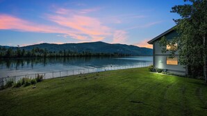 A lakeside property with a house overlooking a calm lake and distant mountains.