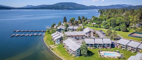 A lakeside resort with multiple buildings, a dock, and a swimming pool.