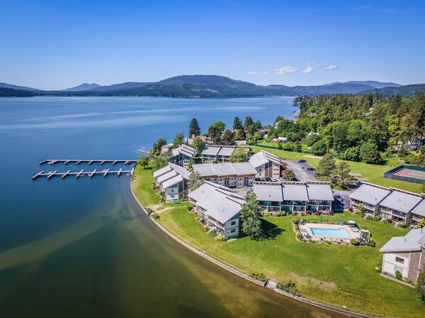 A lakeside resort with multiple buildings, a dock, and a swimming pool.