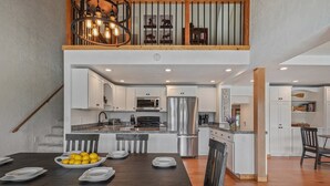 A modern kitchen with white cabinets, stainless steel appliances, and a wooden dining table with plates and lemons.