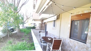 Un patio al aire libre con una mesa y sillas, un muro de piedra y una ventana.