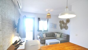 Una sala de estar moderna con un sofá, una mesa de comedor y una lámpara colgante.