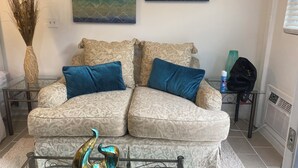 A living room with a patterned sofa, two blue cushions, a decorative metal sculpture, and abstract wall art.